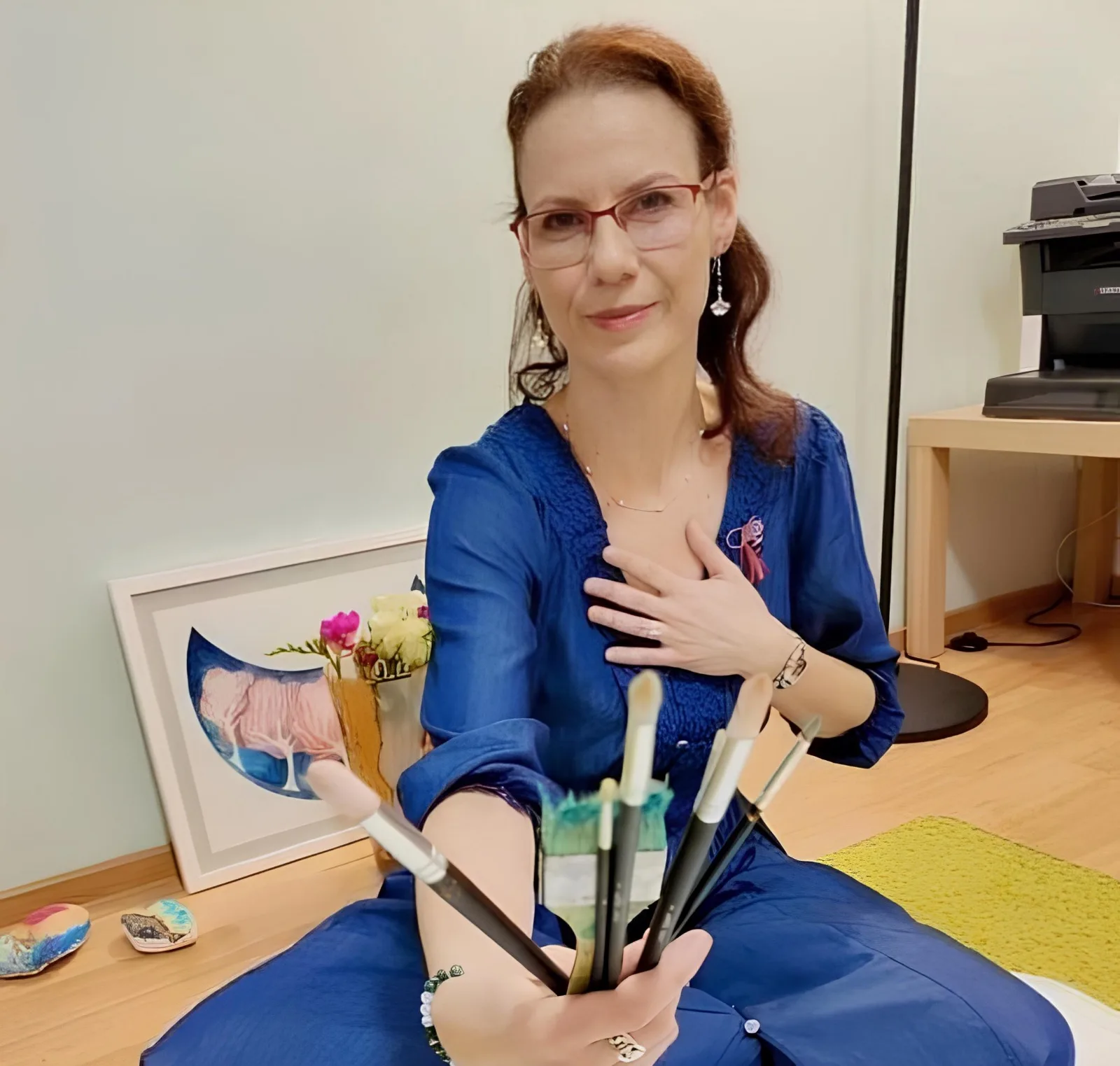 Alina Ioana Beldianu în cabinet, ținând în mână pensulele folosite în terapia expresiv-creativă
